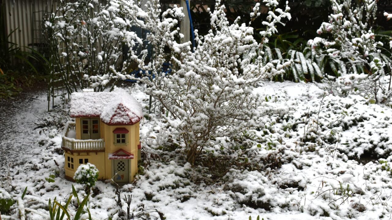 雪が降りだした庭の人形の家20220106